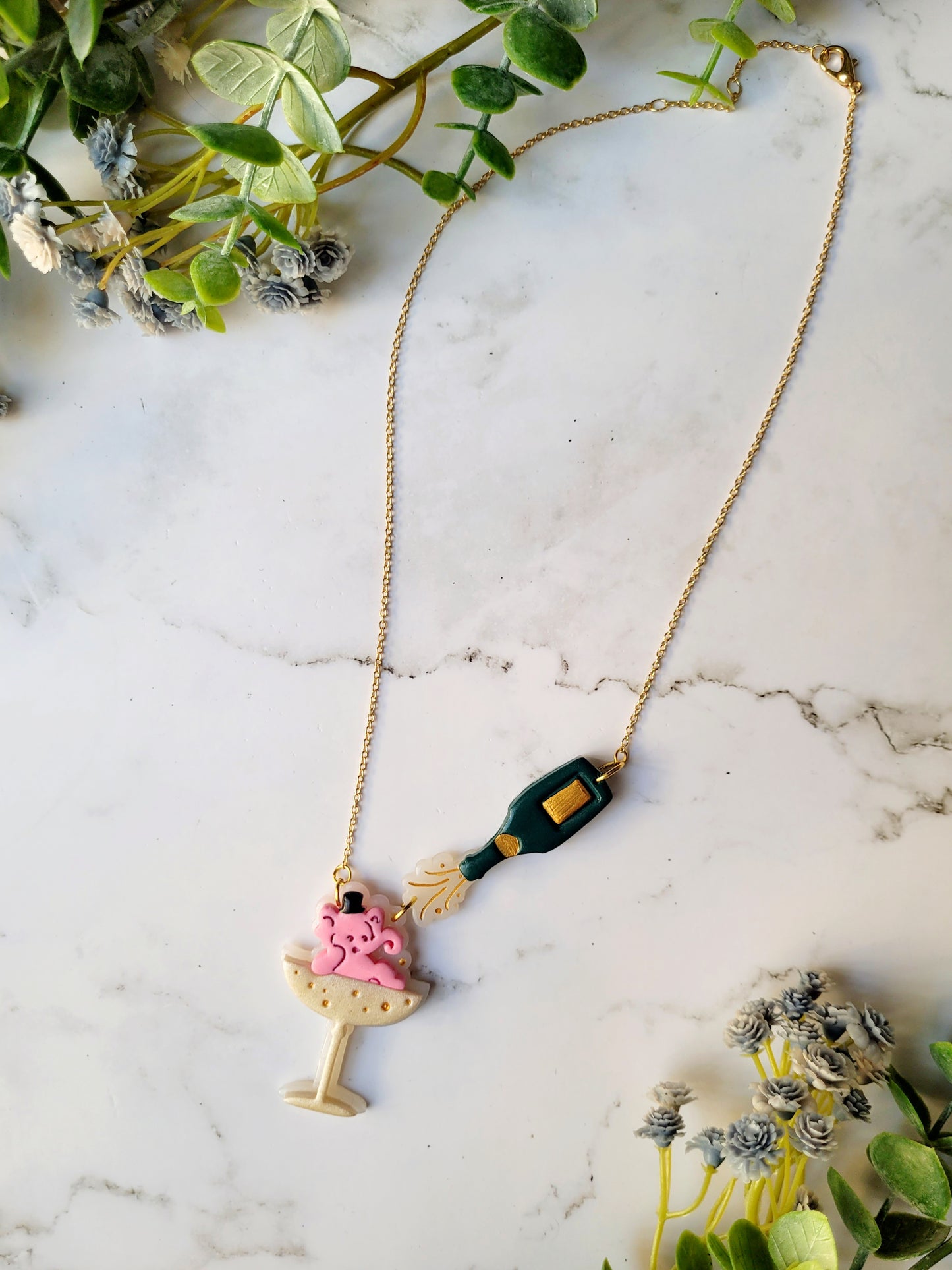 Pink Elephant in a champagne coupe with a champagne bottle necklace on a marble background .