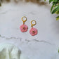 Baby pink flower earrings on white background with foliage. 