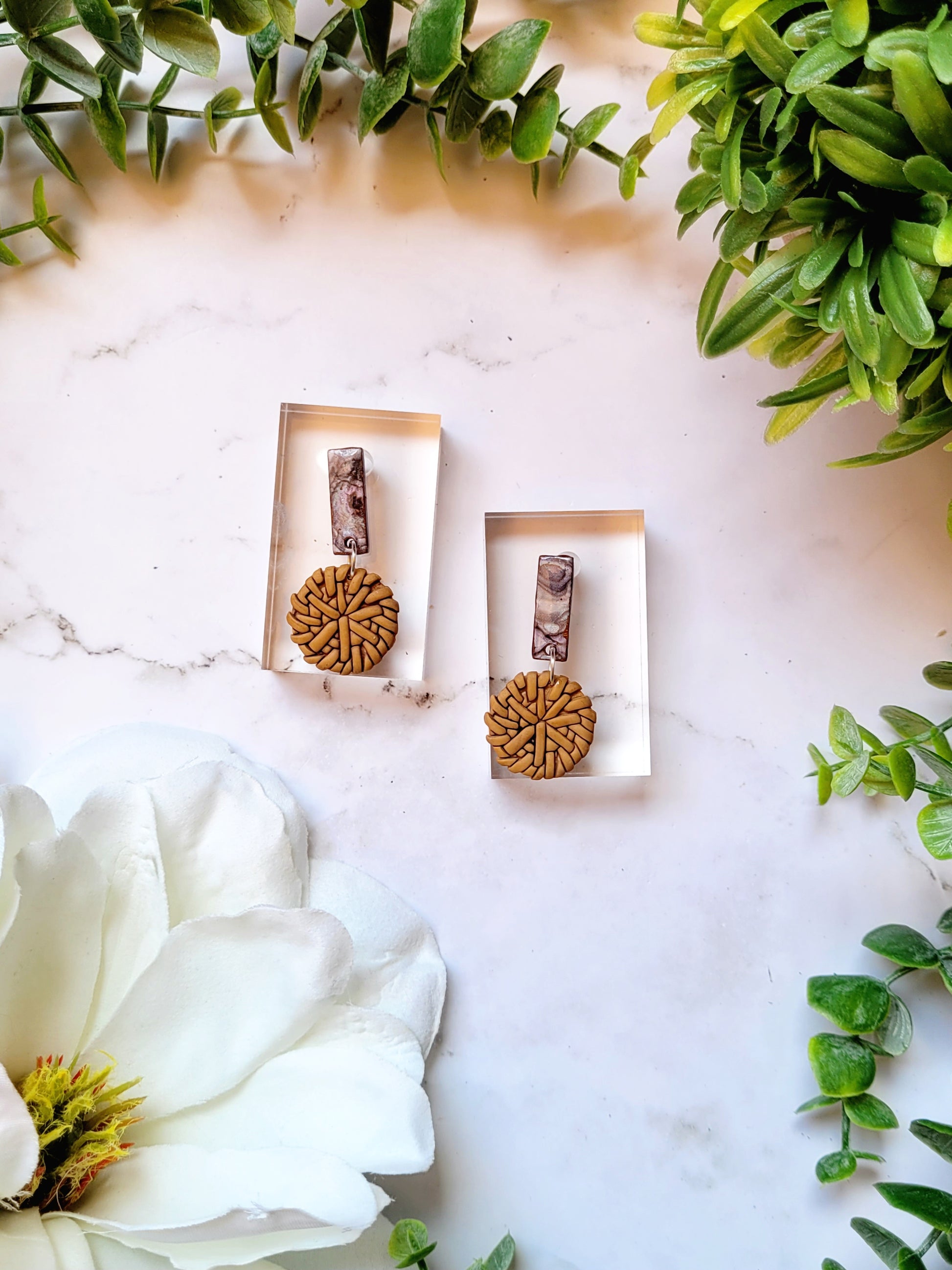 Faux rattan and shell earrings on a marble background. 