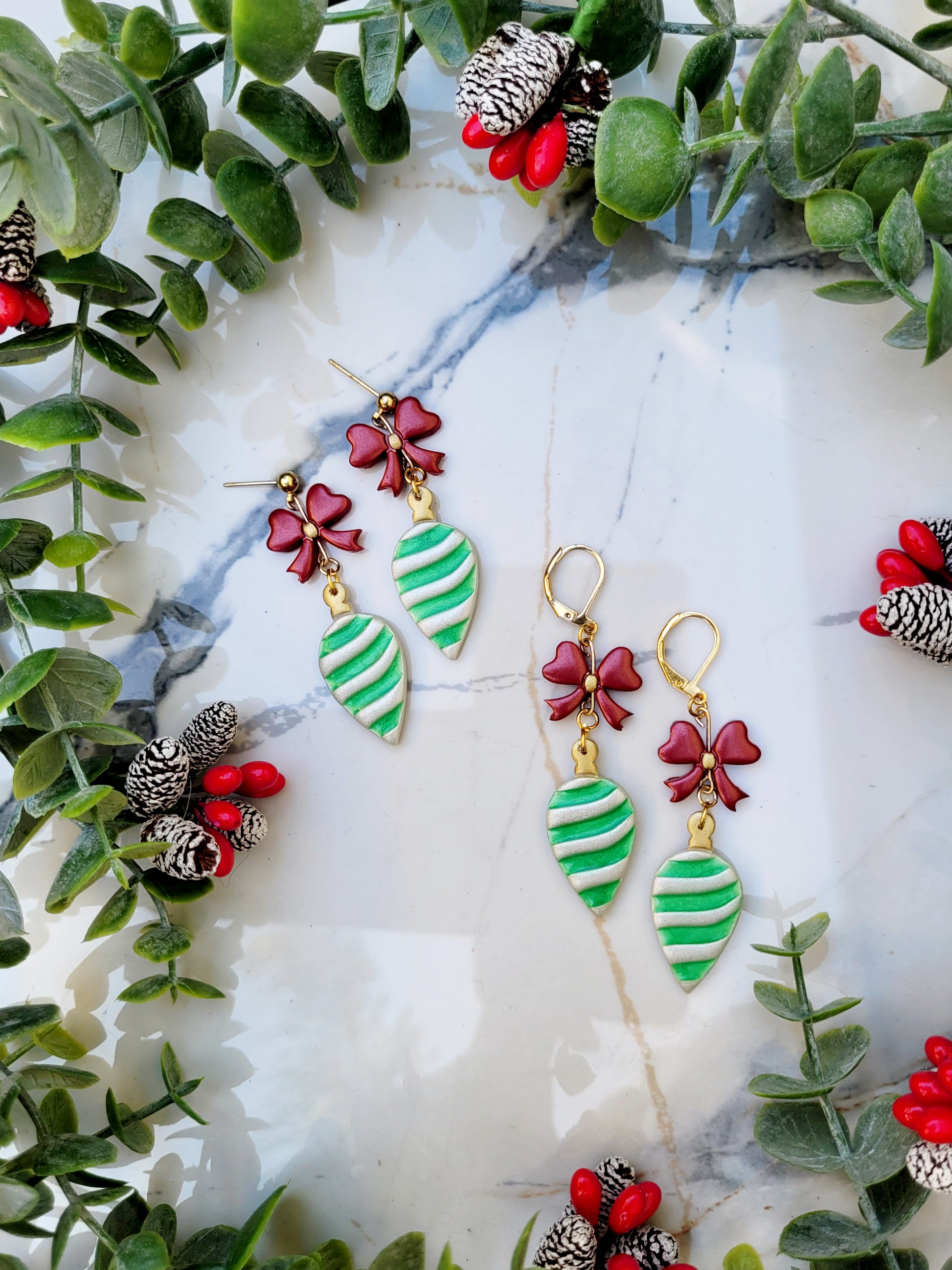 retro ornament style earrings on a marble background surrounded by foliage. 