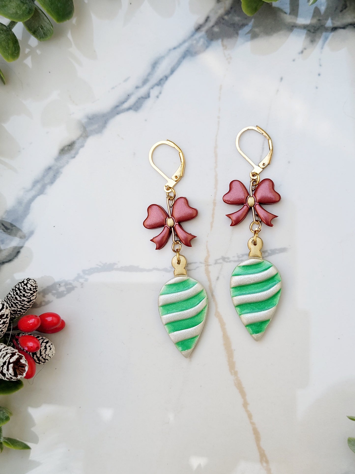 close up of latch back retro ornament style earrings on a marble background surrounded by foliage.