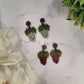 Red and Green grape bunch earrings on a marble background surrounded by foliage 