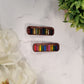 Book hair clips on a white marble background surrounded by foliage. 