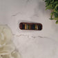 close up of neutral book hair clips on a white marble background surrounded by foliage.