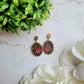 Spring Court Earrings on a marble background surrounded by foliagee