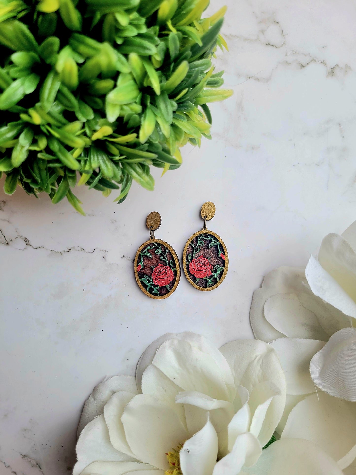 Spring Court Earrings on a marble background surrounded by foliagee