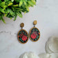 close up of Spring Court Earrings on a marble background surrounded by foliage