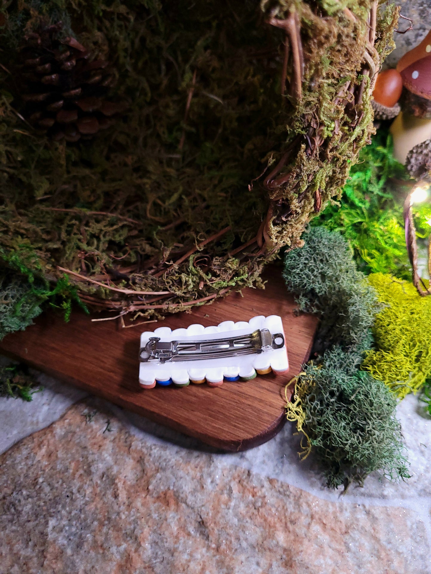 back of Bookstack barrette on a wood and stone background surrounded by moss