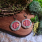 close up of fairy door earrings on wood and stone background surrounded by moss