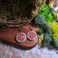 fairy door earrings on wood and stone background surrounded by moss