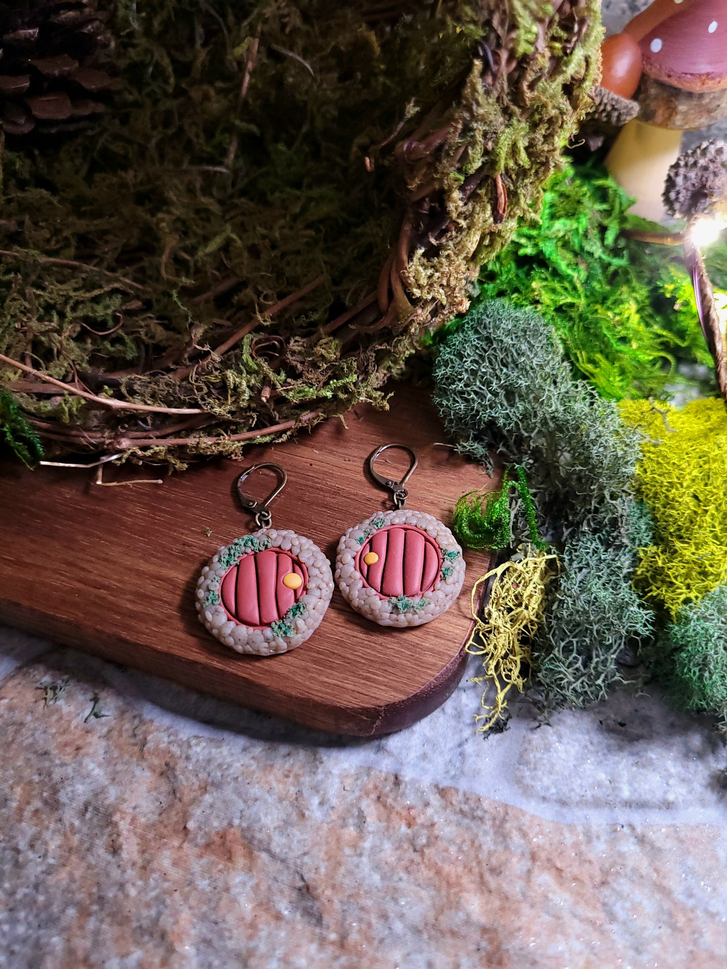 fairy door earrings on wood and stone background surrounded by moss