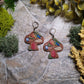 Mushroom Shelf Earring on a stone background surrounded by foliage. 