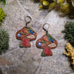 close up of Mushroom Shelf Earring on a stone background surrounded by foliage. 