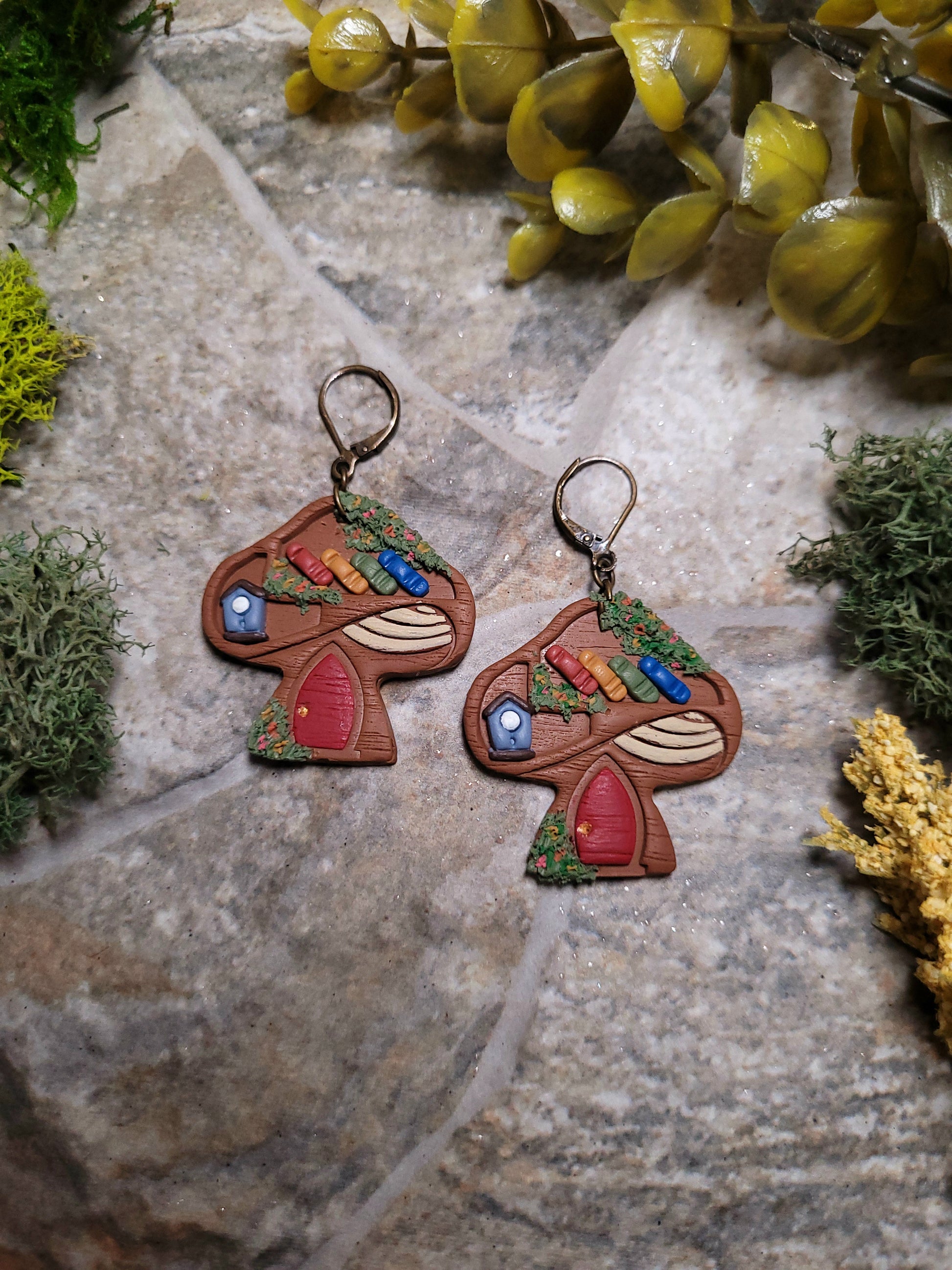 close up of Mushroom Shelf Earring on a stone background surrounded by foliage. 