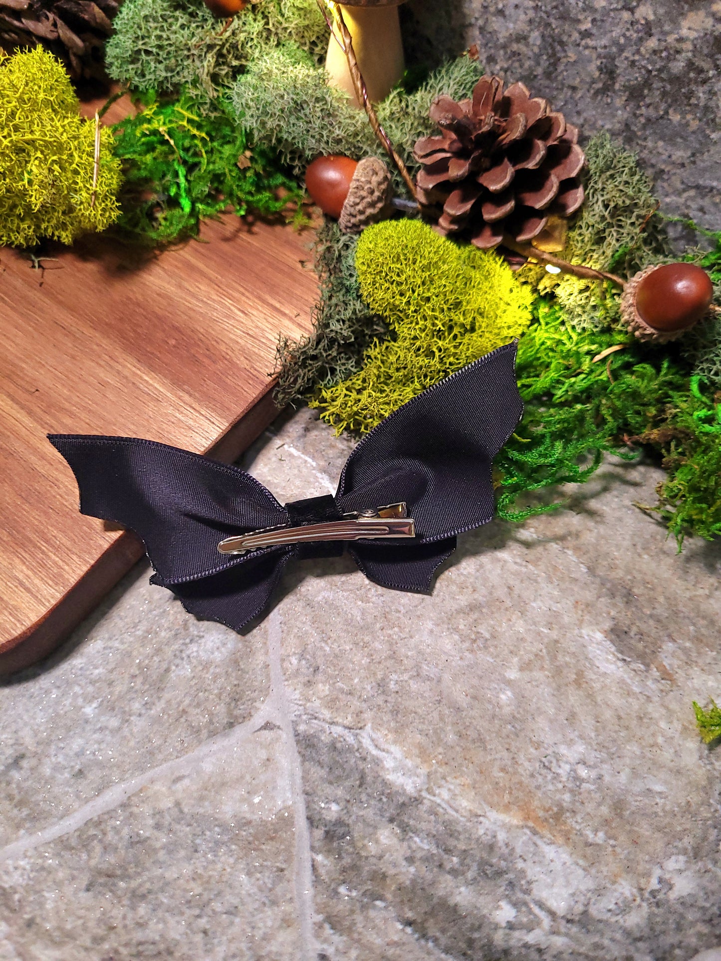 Back of bat bow on wood and stone background surrounded by foliage 