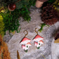 Shroom earrings on a stone background surrounded by foliage. 