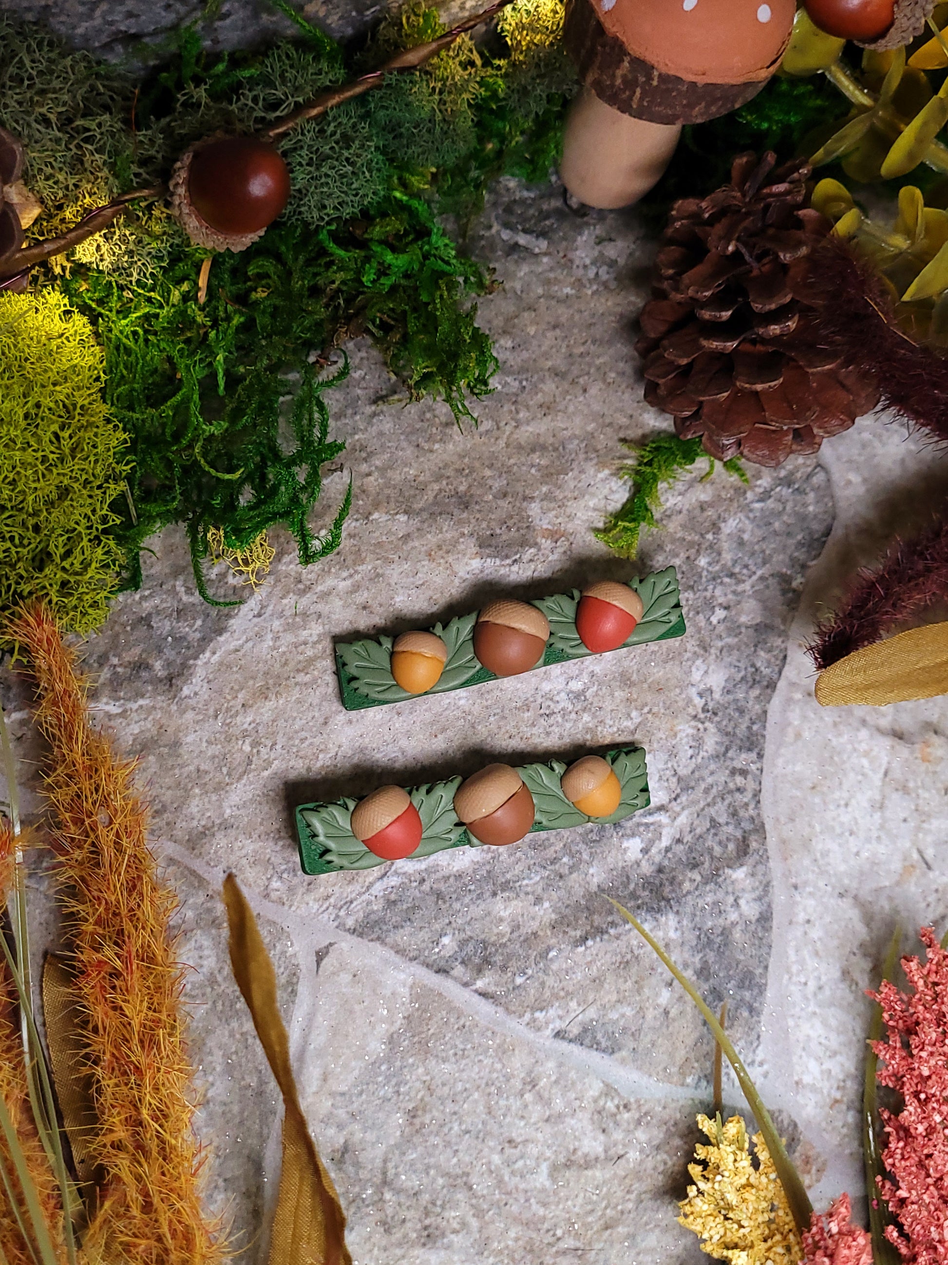 two acorn clips on a stone background surrounded by foliage