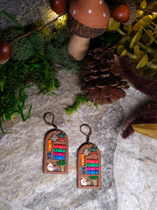 ACOTAR inspired bookshelf earrings on a stone background surrounded by foliage