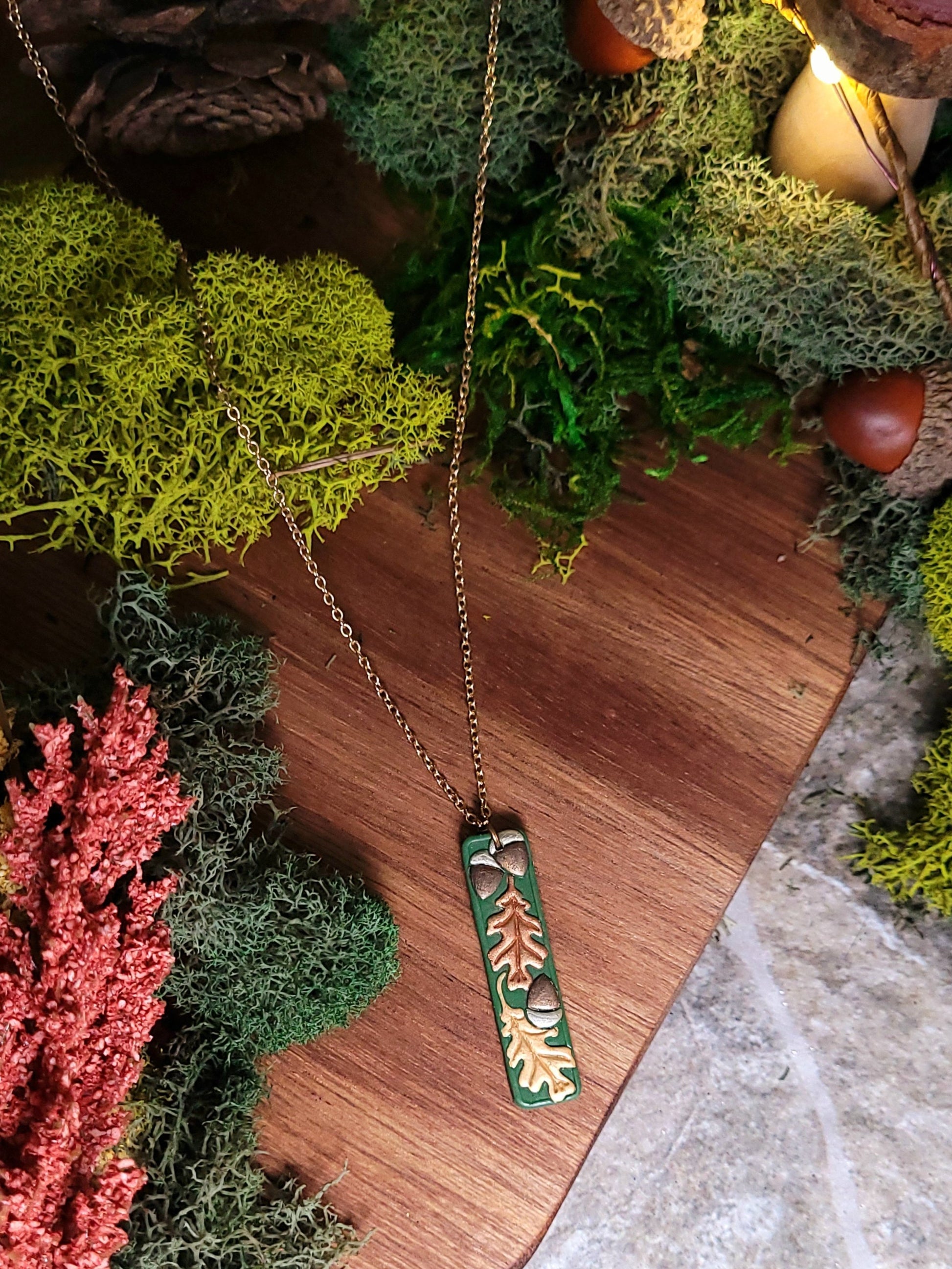 close up of the Green bar shaped pendant with metallic acorns and oak leaves.