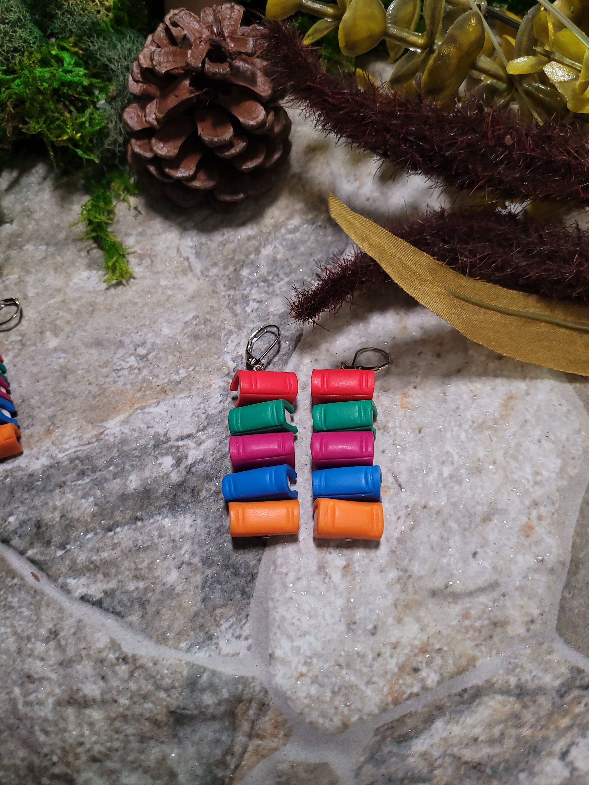 Bookstack earrings made of polymer clay in regular size sits on a stone background surrounded by foliage.