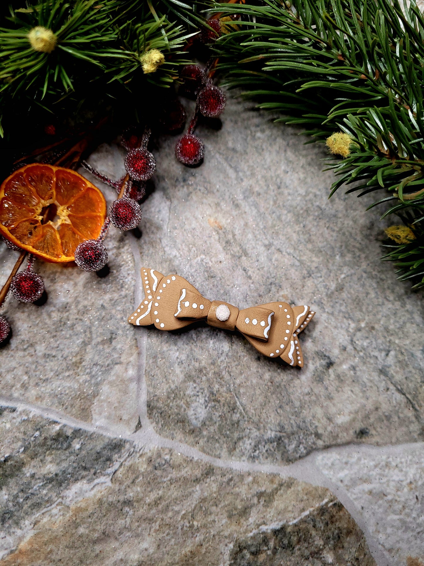 Gingerbread Bow Barrettes on a  stone background surrounded by foliage