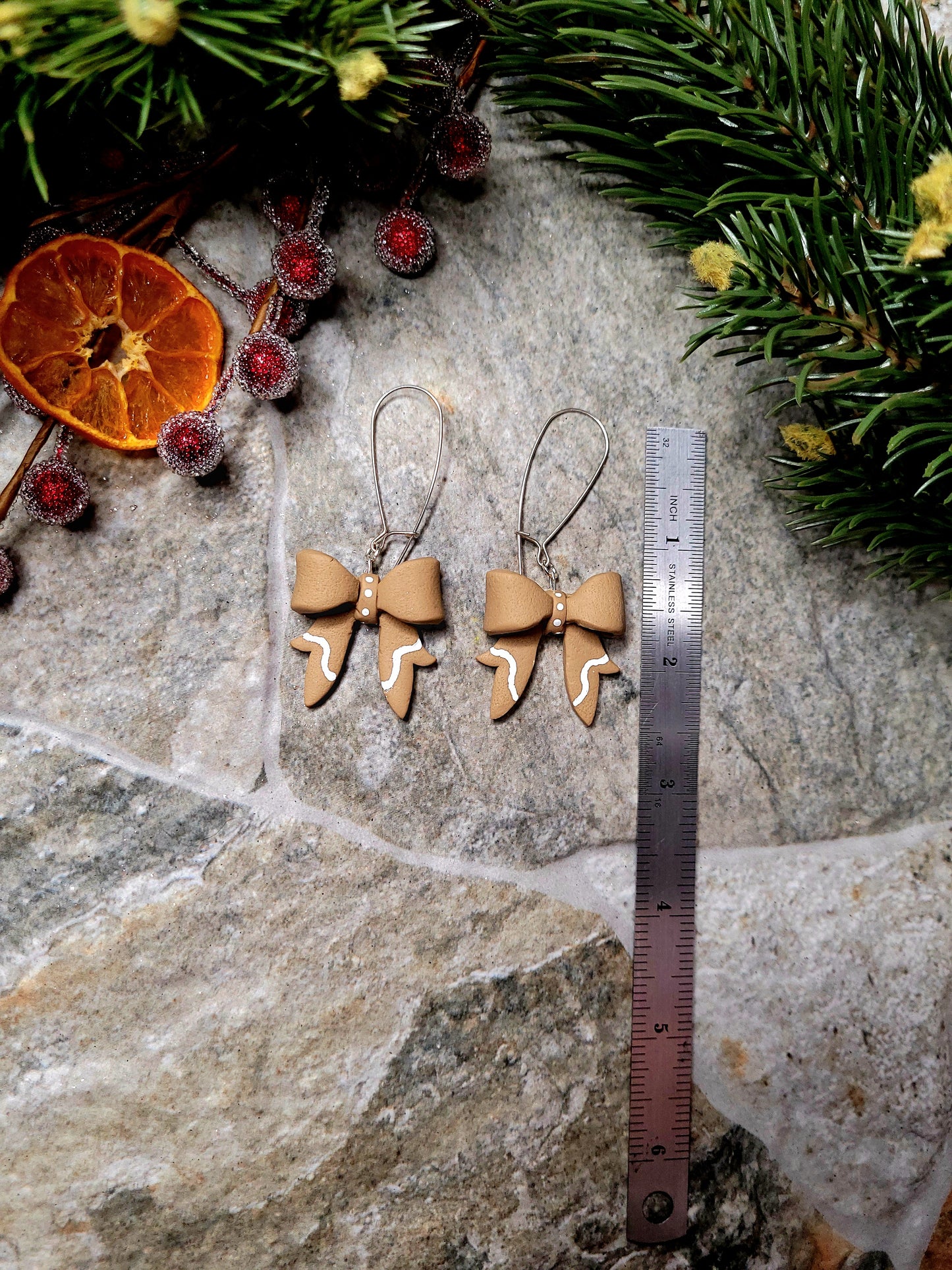 Gingerbread Bow earrings on a  stone background surrounded by foliage