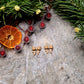 Gingerbread Bow studs on a stone background surrounded by foliage