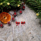 Santa Bow studs on a stone background surrounded by foliage