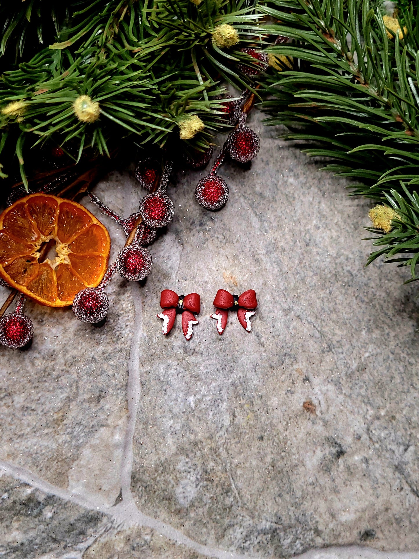 Santa Bow studs on a stone background surrounded by foliage