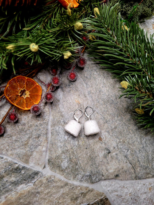 white Gumdrop earrings on a  stone background surrounded by foliage