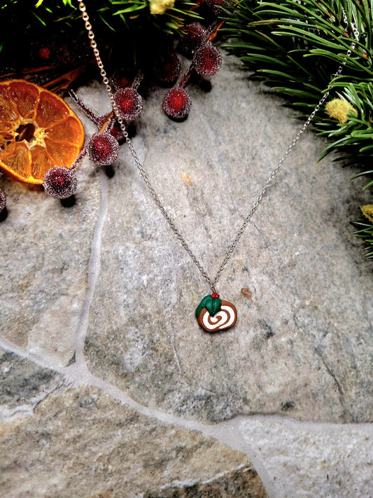 yule log necklace on a  stone background surrounded by foliage. 