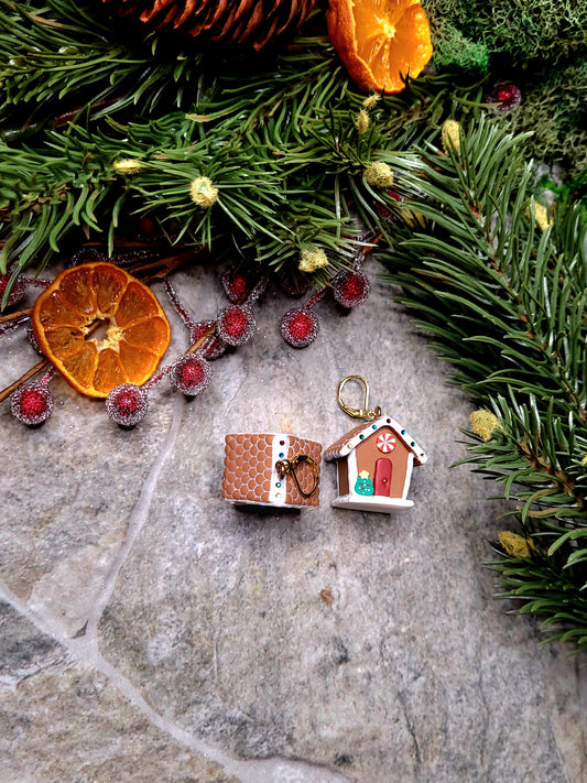 side and top view of Gingerbread house earrings on a stone background surrounded by foliage. 