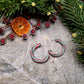 Retro Candy Cane Hoop Earring on a  stone background surrounded by foliage. 