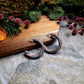 Retro Candy Cane Hoop Earring on a  wood and stone background surrounded by foliage. 