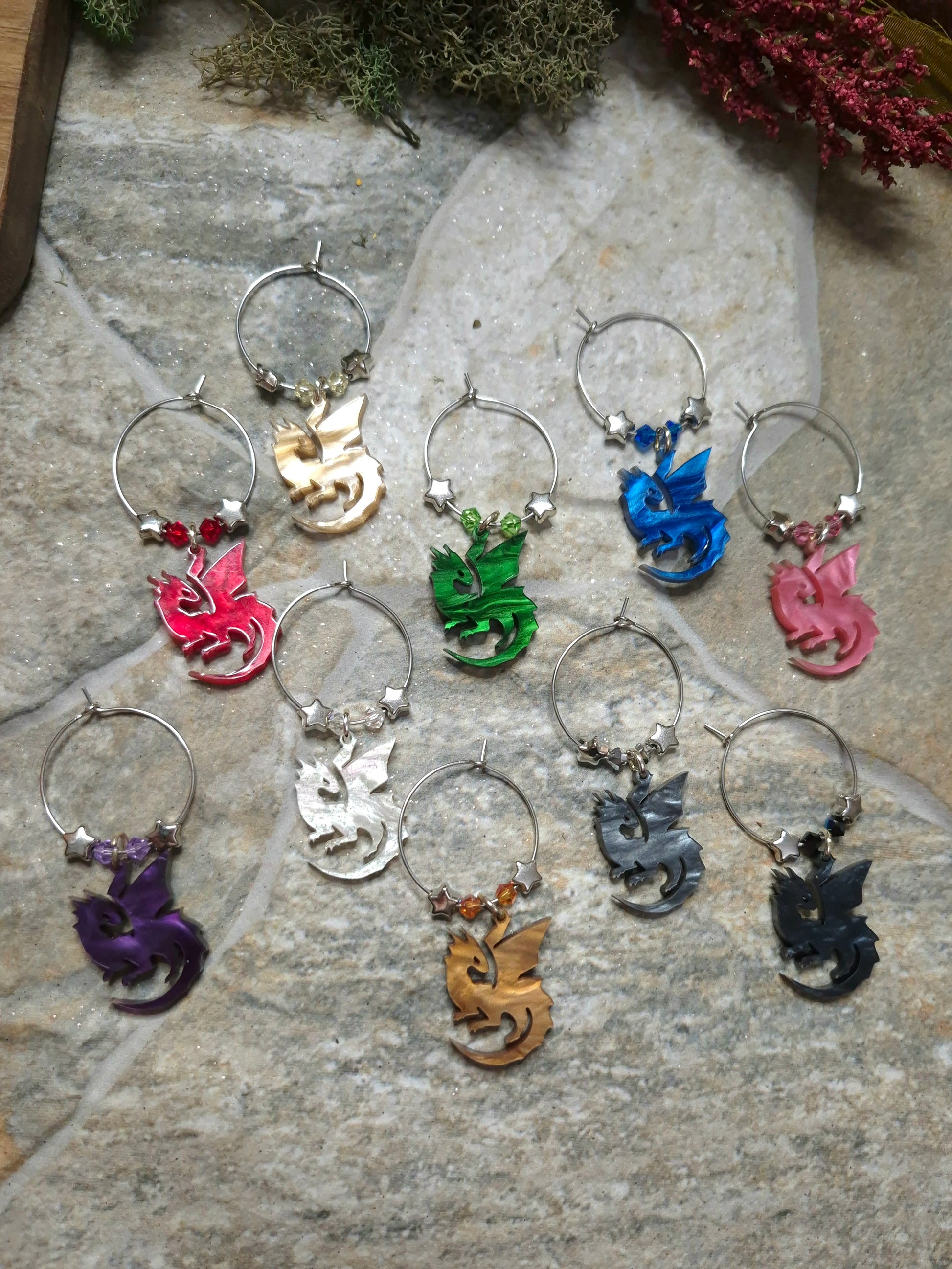 Set of colorful wine charms with dragon designs on a stone surface