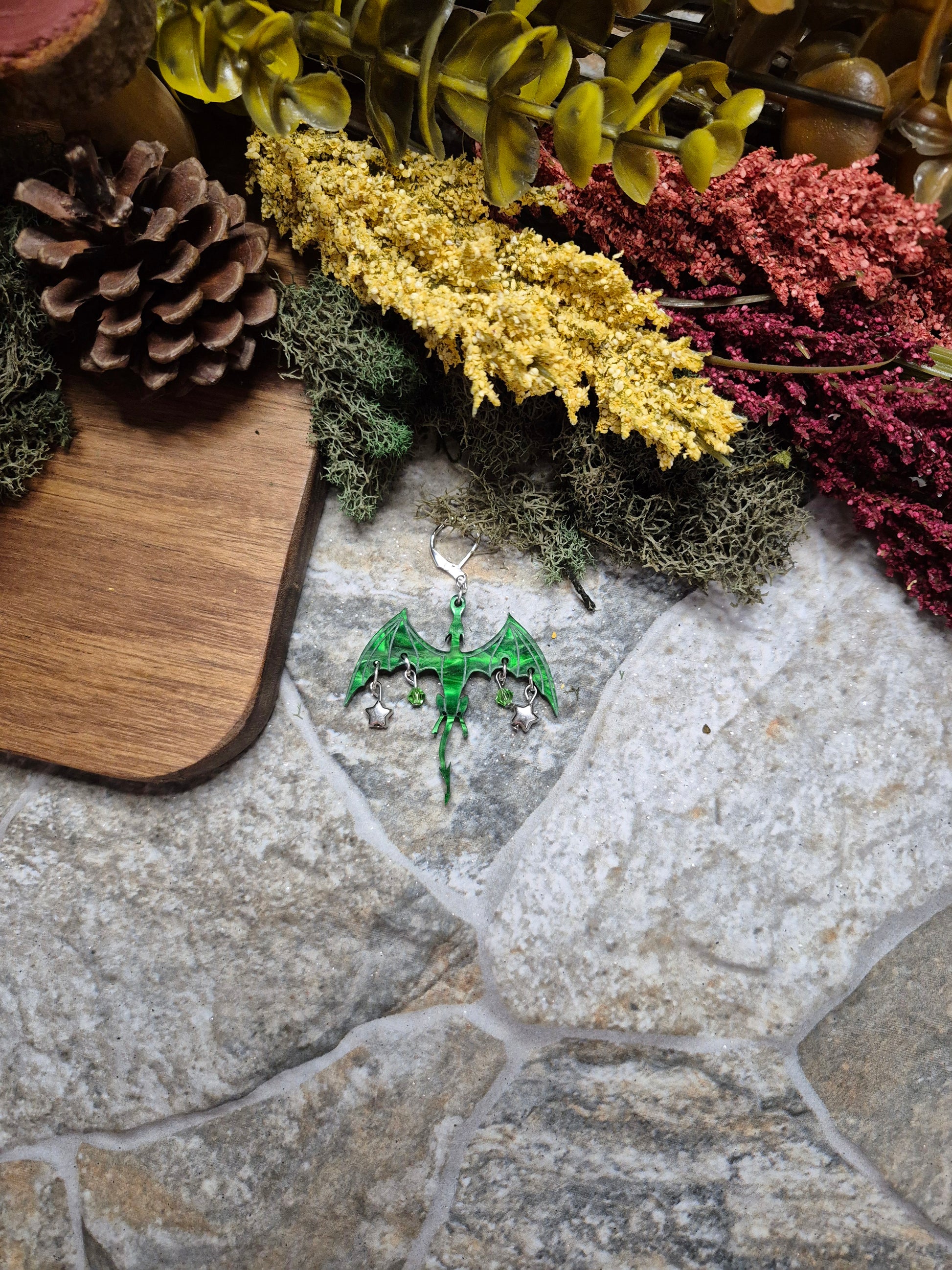 green dragon dangle on a stone background surrounded by foliage. 