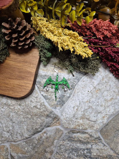 green dragon dangle on a stone background surrounded by foliage. 