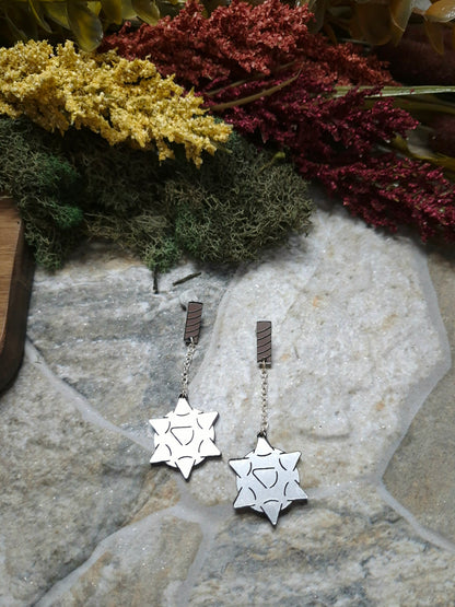 flail earrings on a stone background surrounded by foliage. 