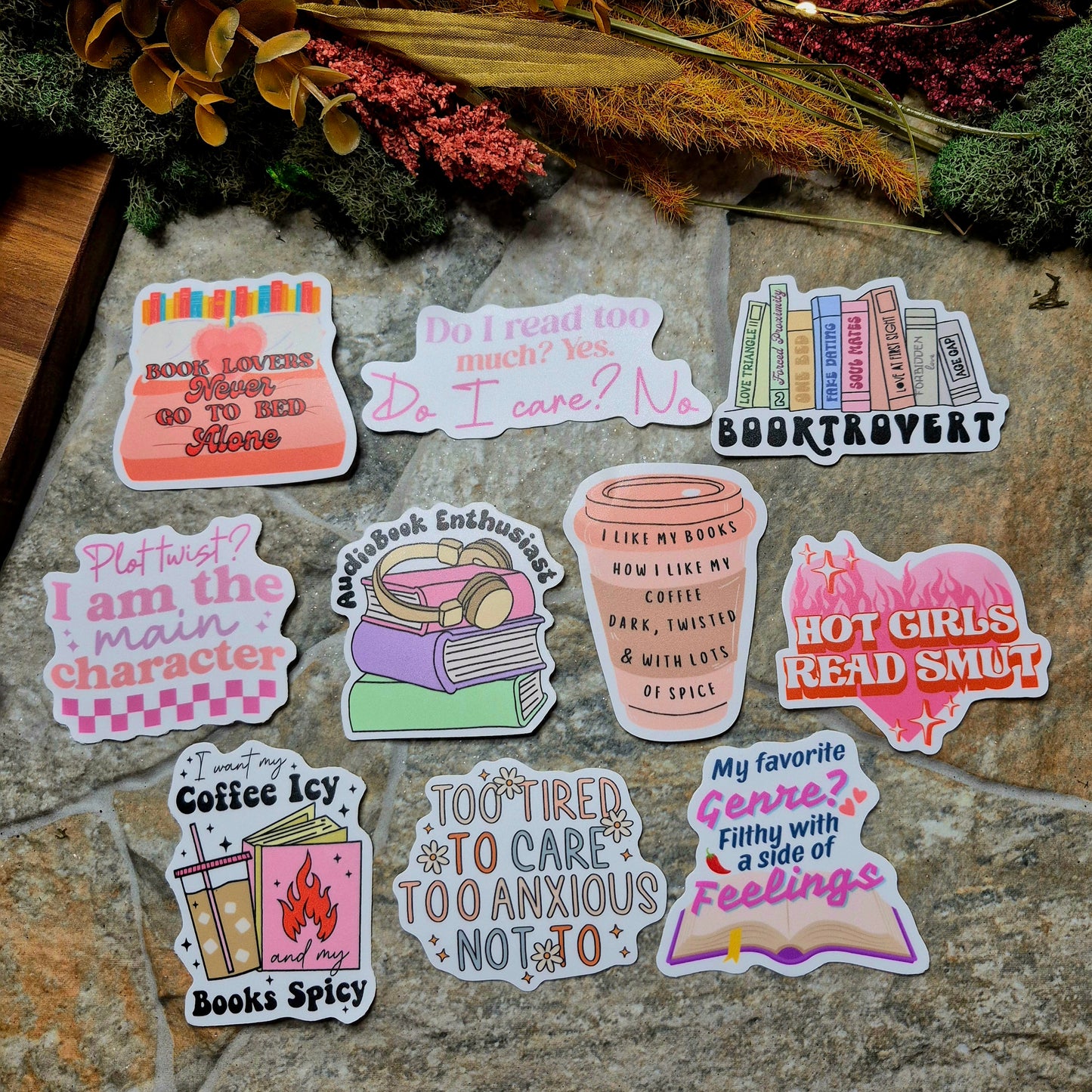 Collection of book-themed stickers on a stone surface with decorative plants.