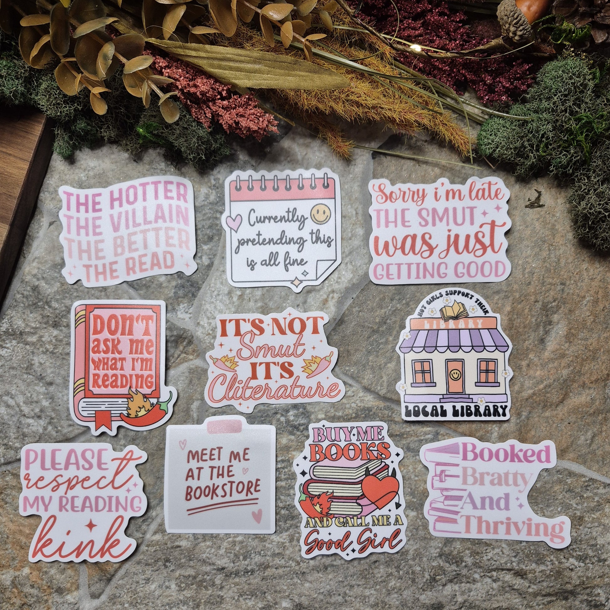 Set of literary-themed stickers on a stone surface with plants in the background