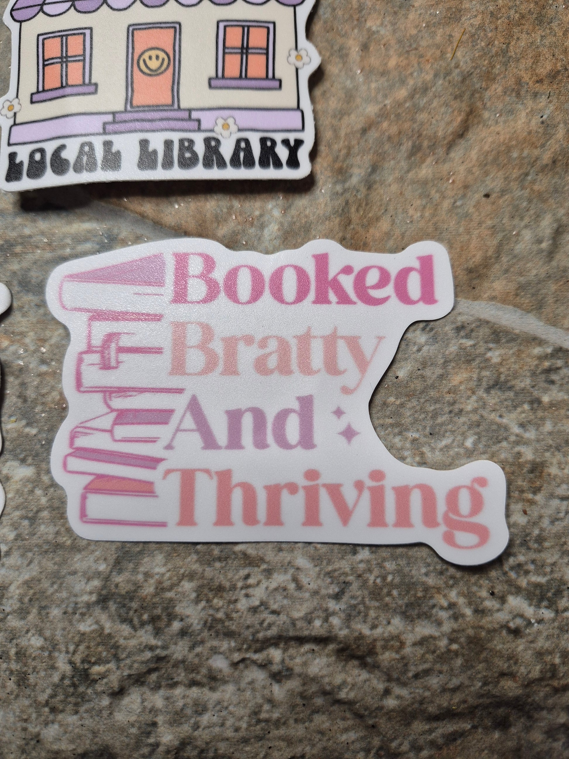 Booked Bratty Thriving Sticker on stone background 