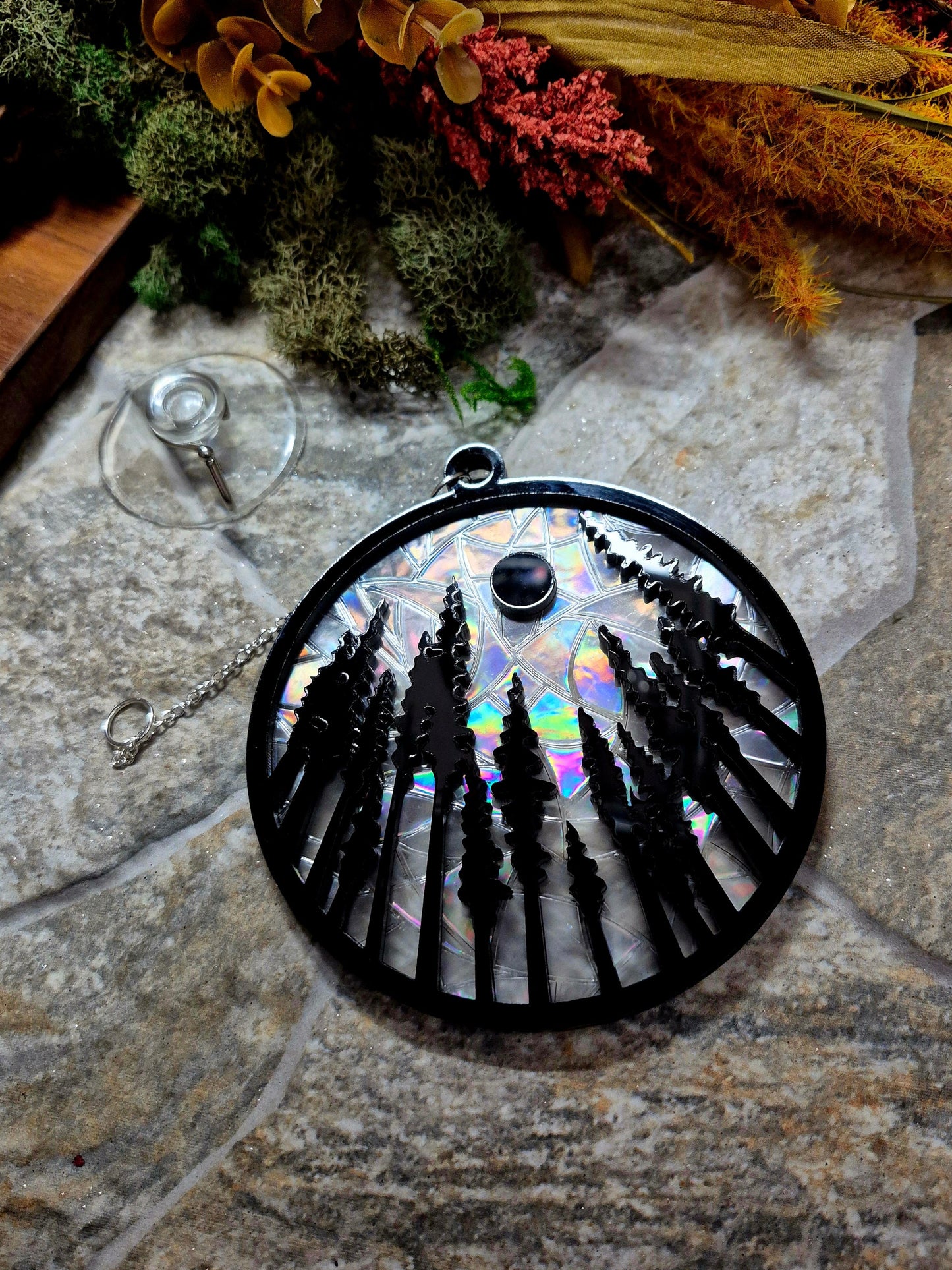 Forest suncatcher on a stone background surrounded by foliage 
