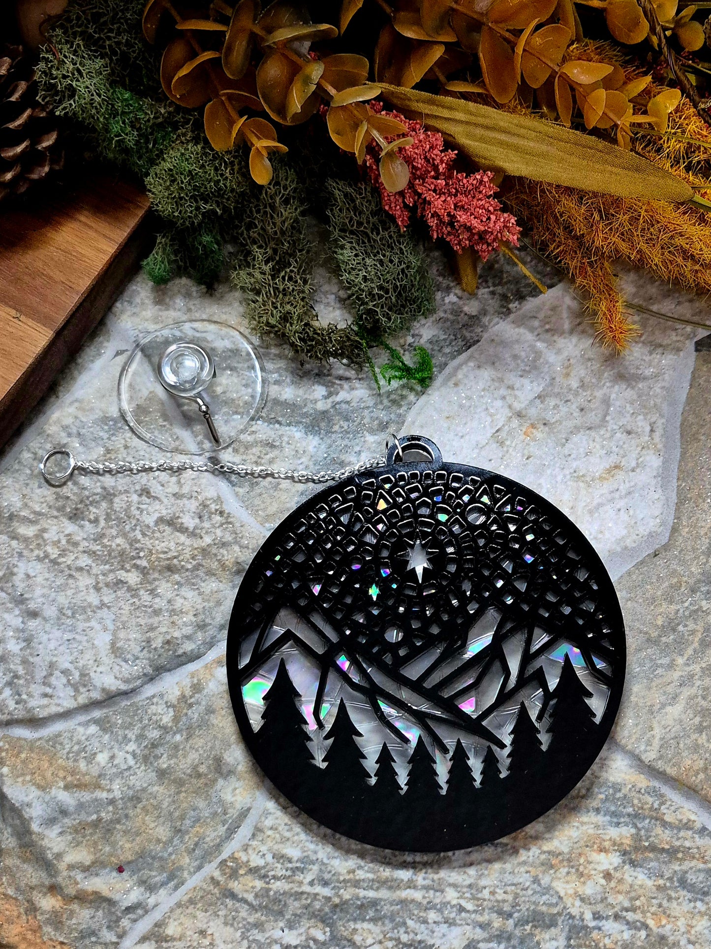 Starry Mountain suncatcher on a stone background surrounded by foliage 
