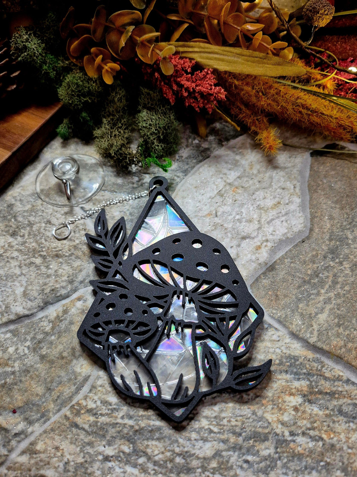 Mushroom suncatcher on a stone background surrounded by foliage 
