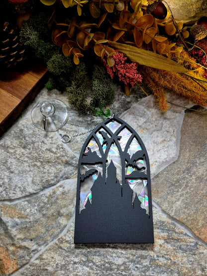 Gothic Dragon Window Suncatcher on a stone background surrounded by foliage 
