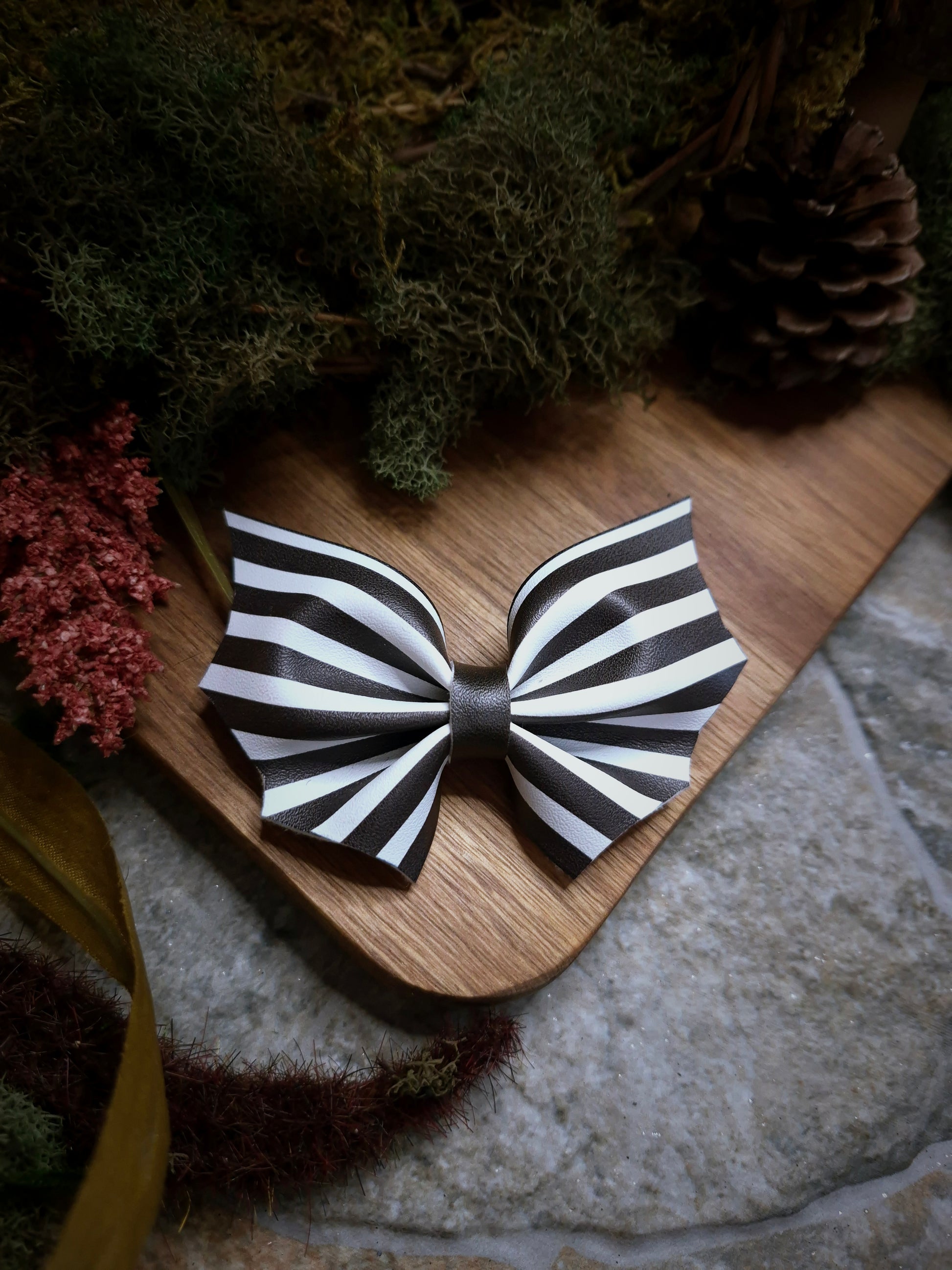 Beetlejuice stripe bat bow on a wood and stone background 