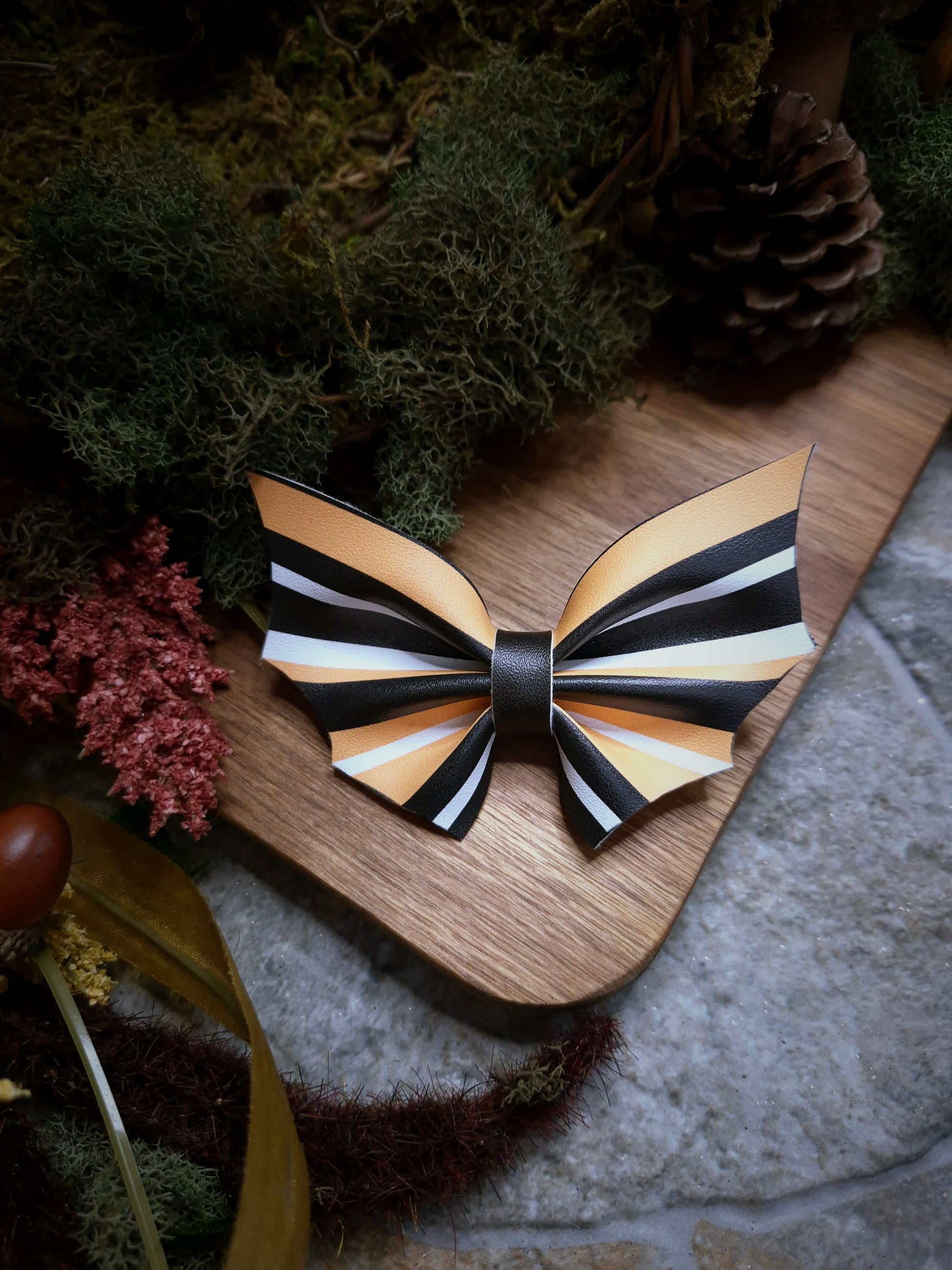 Halloween stripe bat bow on a wood and stone background 