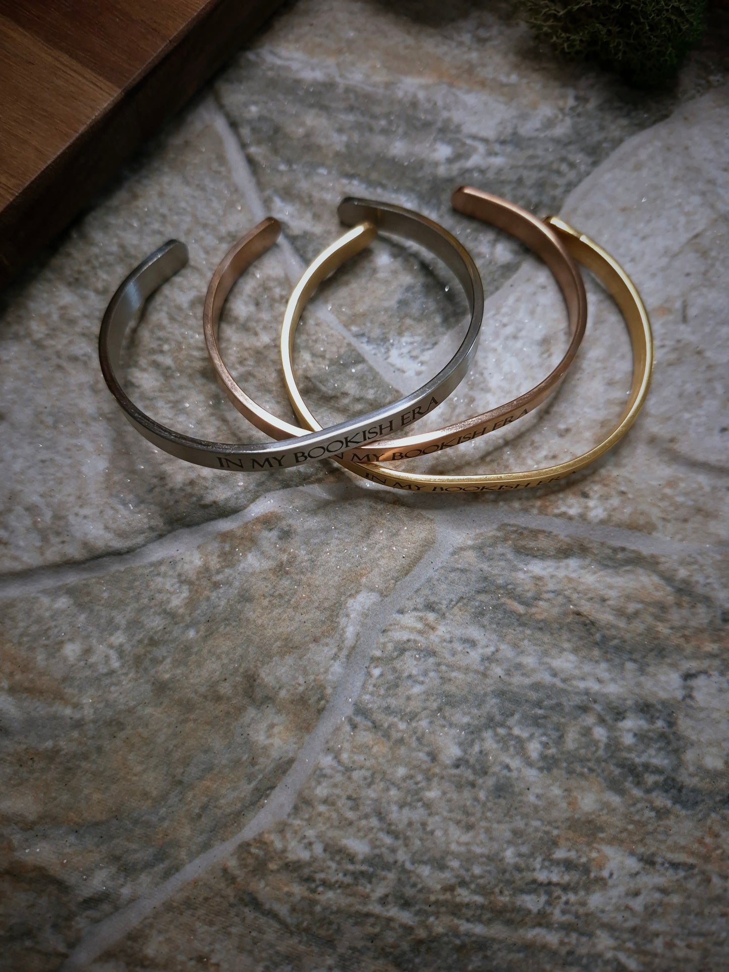 Side view of stack of In My Bookish Era bracelets on a stone background. 