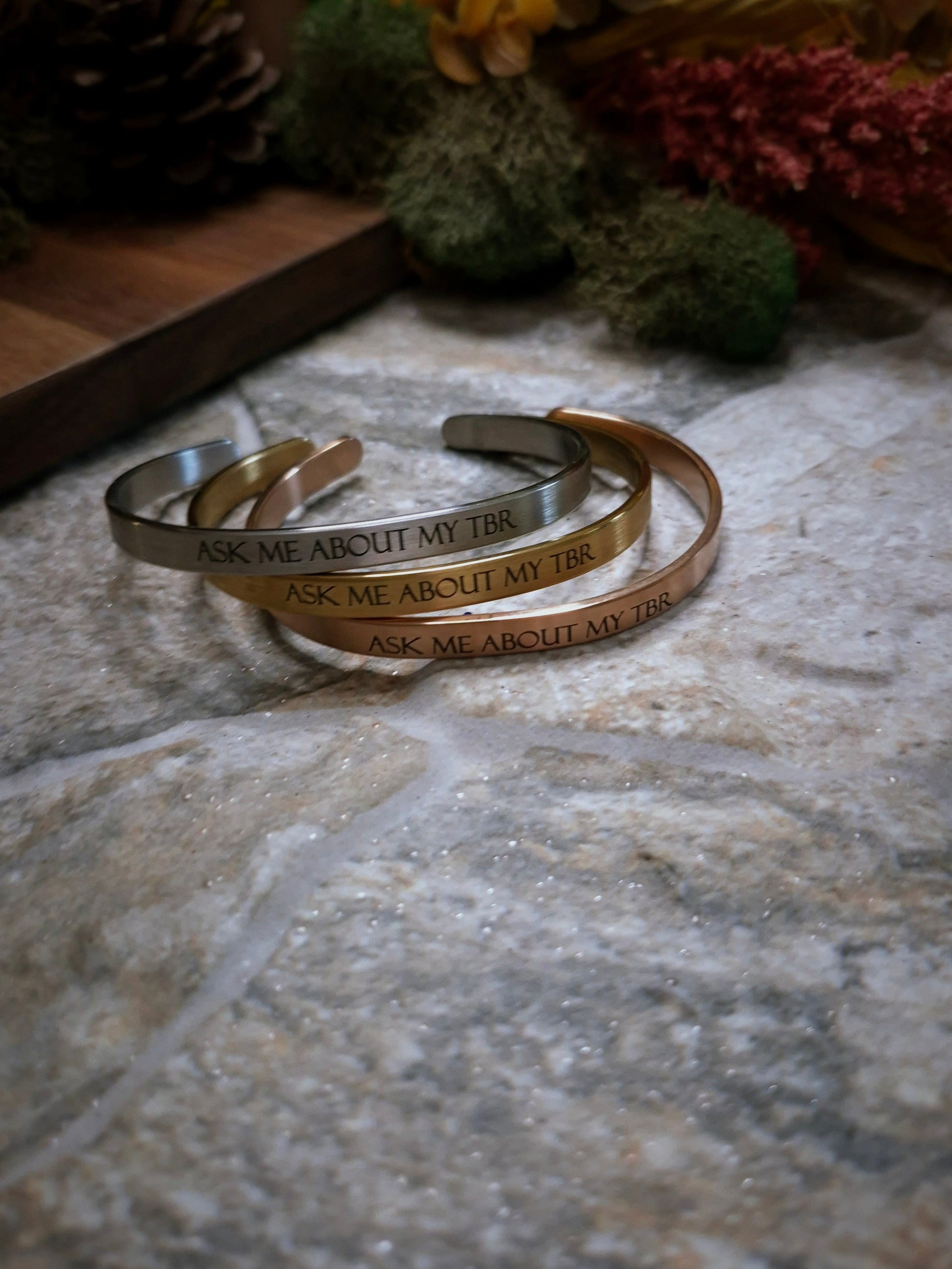 Stack of Ask Me About My TBR bracelets on a stone background. 