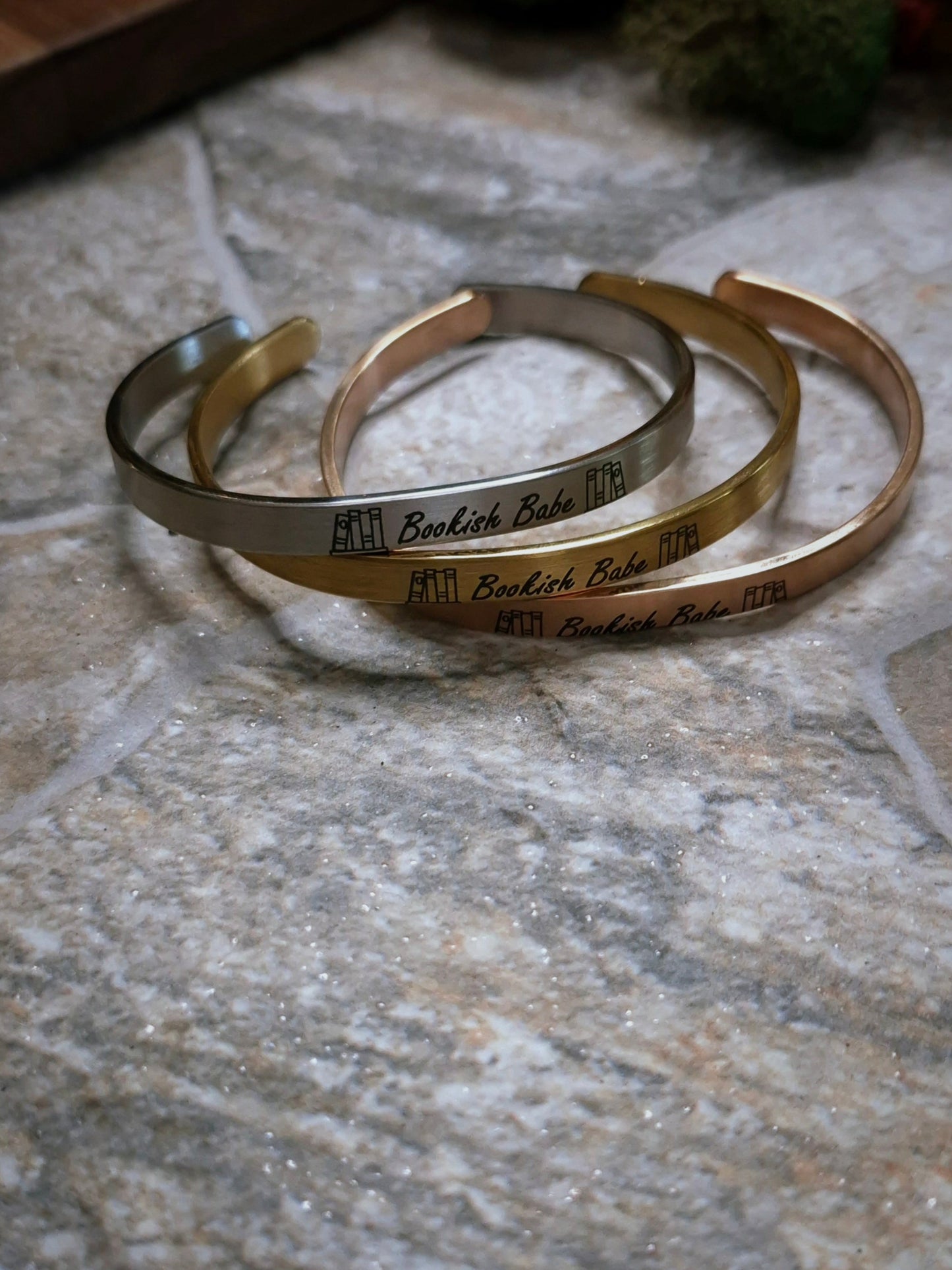Stack of Bookish Babe bracelets on a stone background. 